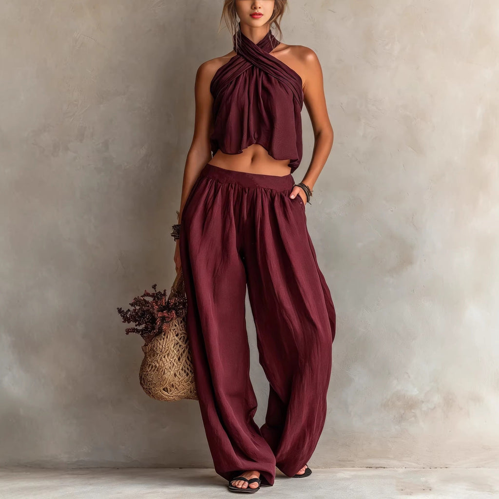 Woman wearing a burgundy halter top and wide-leg pants against a neutral background