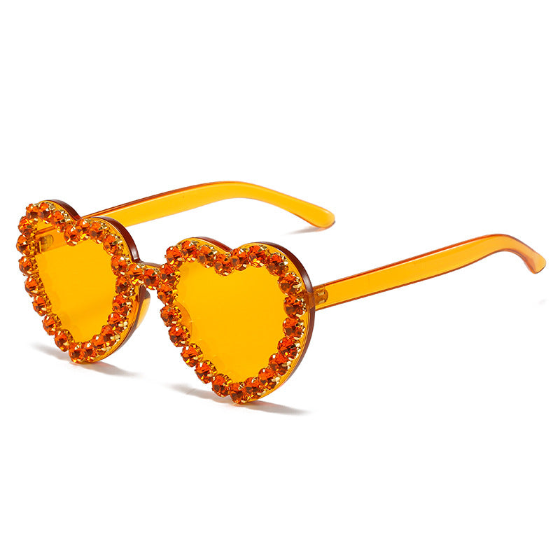 Heart-shaped sunglasses with orange lenses and embellishments on a white background