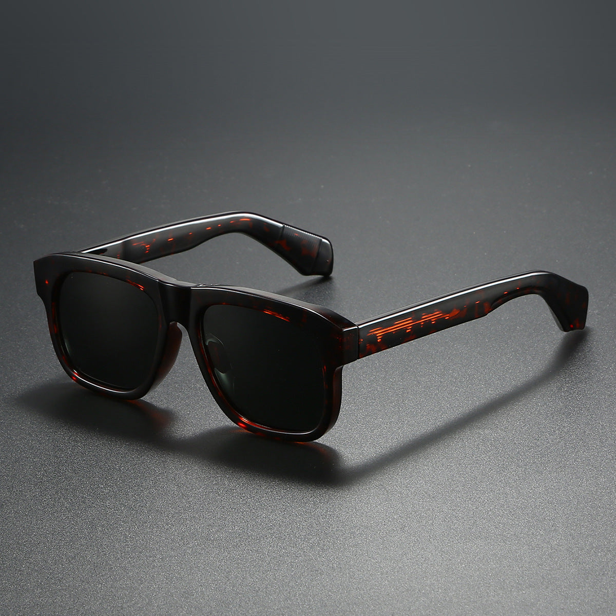 Sunglasses with tortoiseshell frame and dark lenses on a gray background