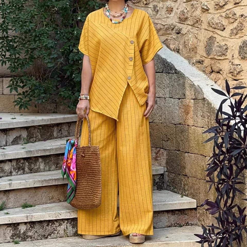 Person wearing a yellow outfit standing on stone steps with a stone wall and plants in the background
