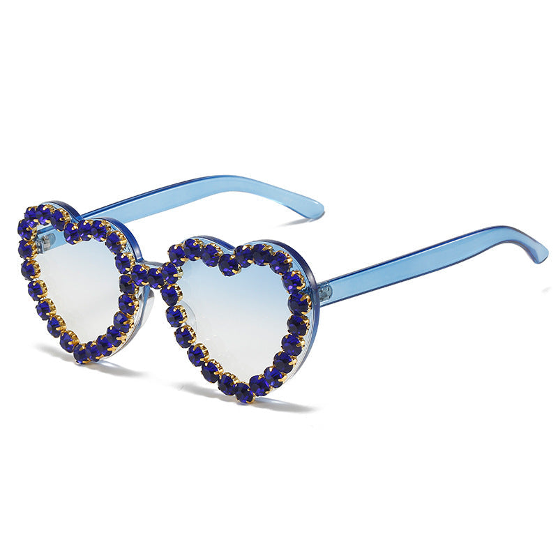 Heart-shaped sunglasses with blue frame and purple gemstones on a white background