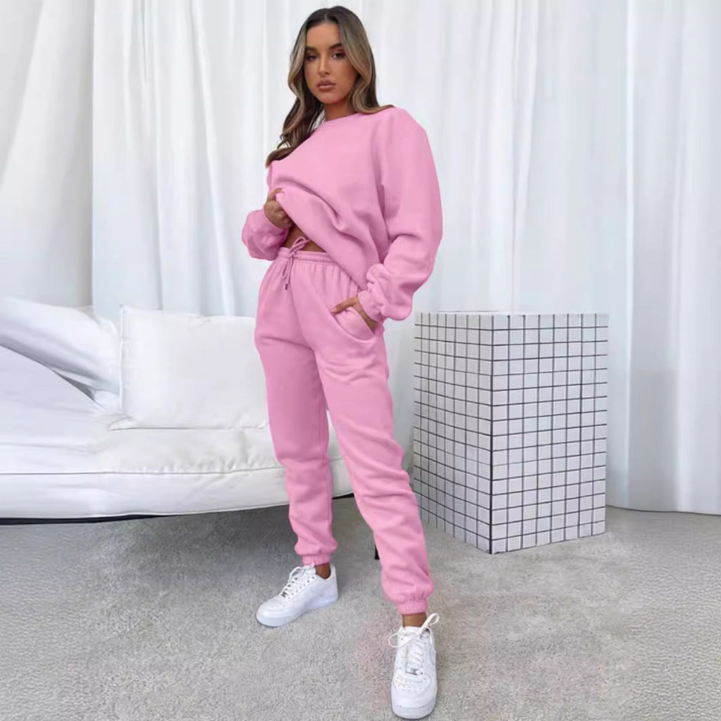 Woman wearing a pink tracksuit in a minimalistic room.