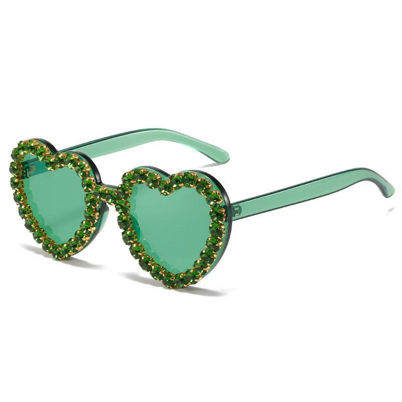 Green heart-shaped sunglasses with decorative elements on a white background