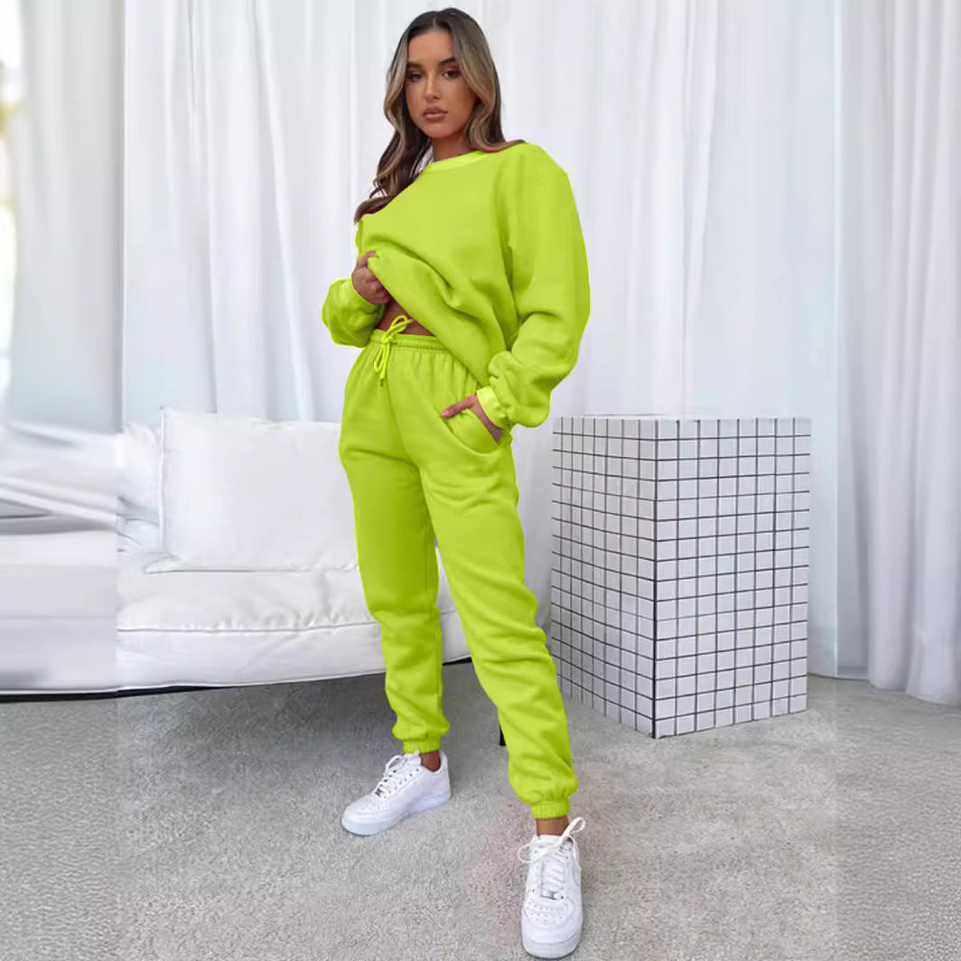 Woman wearing a bright green tracksuit in a minimalistic room.