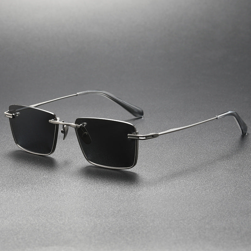 Sunglasses with thin metal frame and black lenses on a gray background