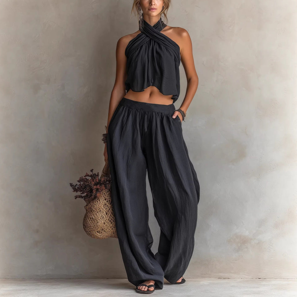 Woman wearing a black halter top and wide-leg pants against a neutral background