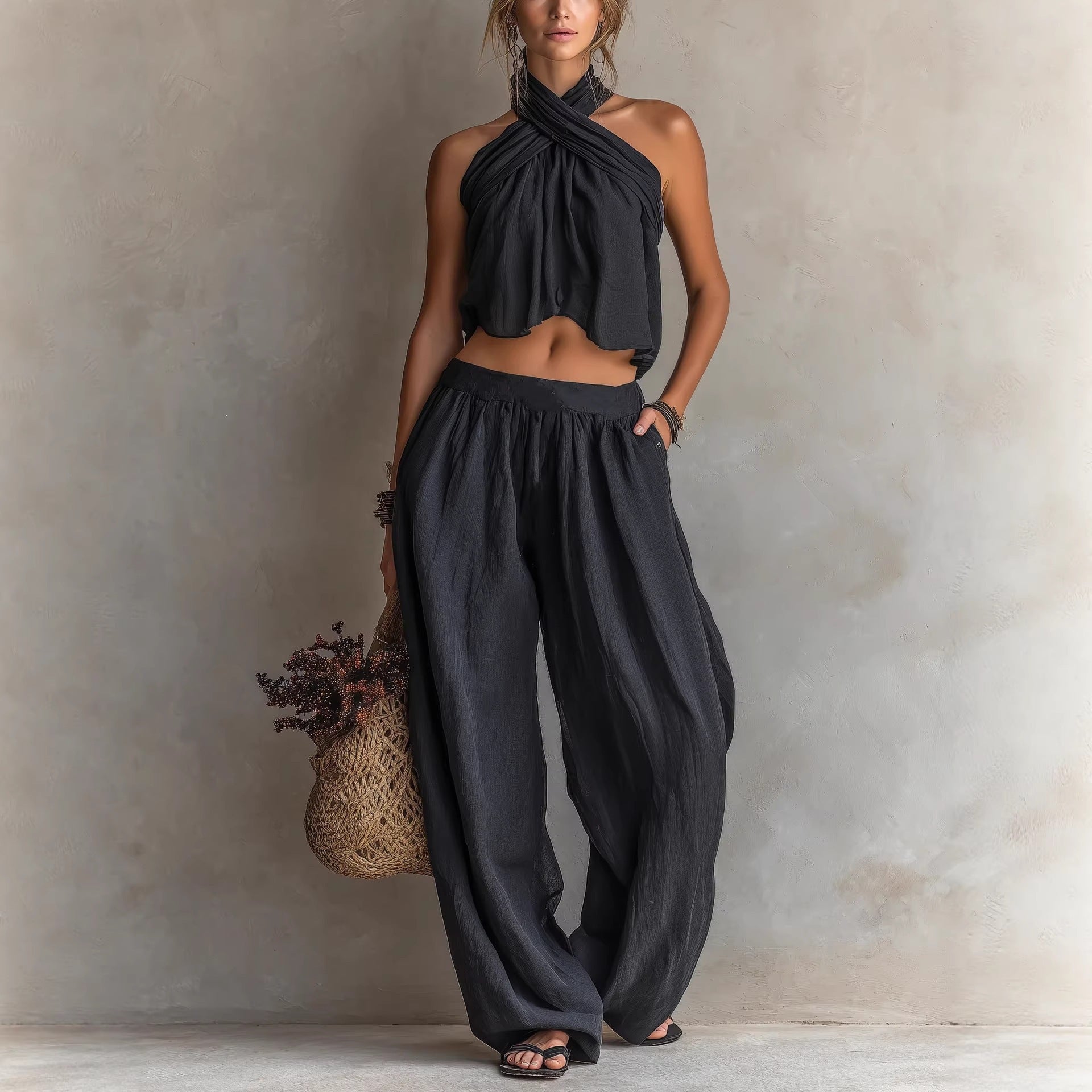 Woman wearing a black halter top and wide-leg pants against a neutral background