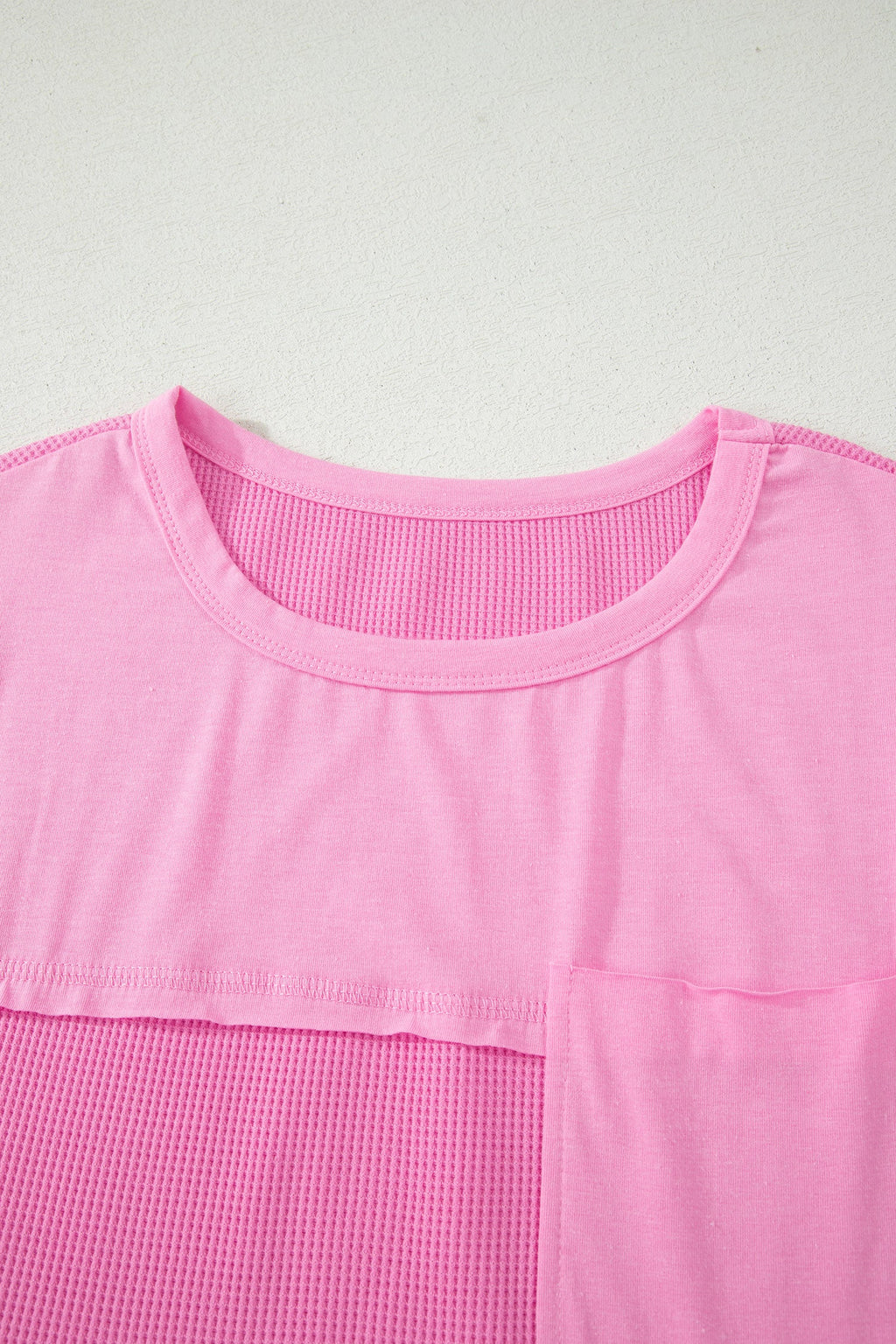 Close-up of a pink top with a textured pattern on a light gray background