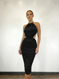 Woman wearing a black halter neck dress against a white wall