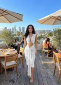Woman in a white dress standing on a rooftop with a cityscape in the background