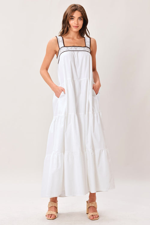 Woman wearing a white dress with thin straps on a plain background