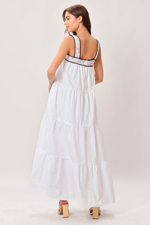 Woman wearing a white dress with black straps on a plain background