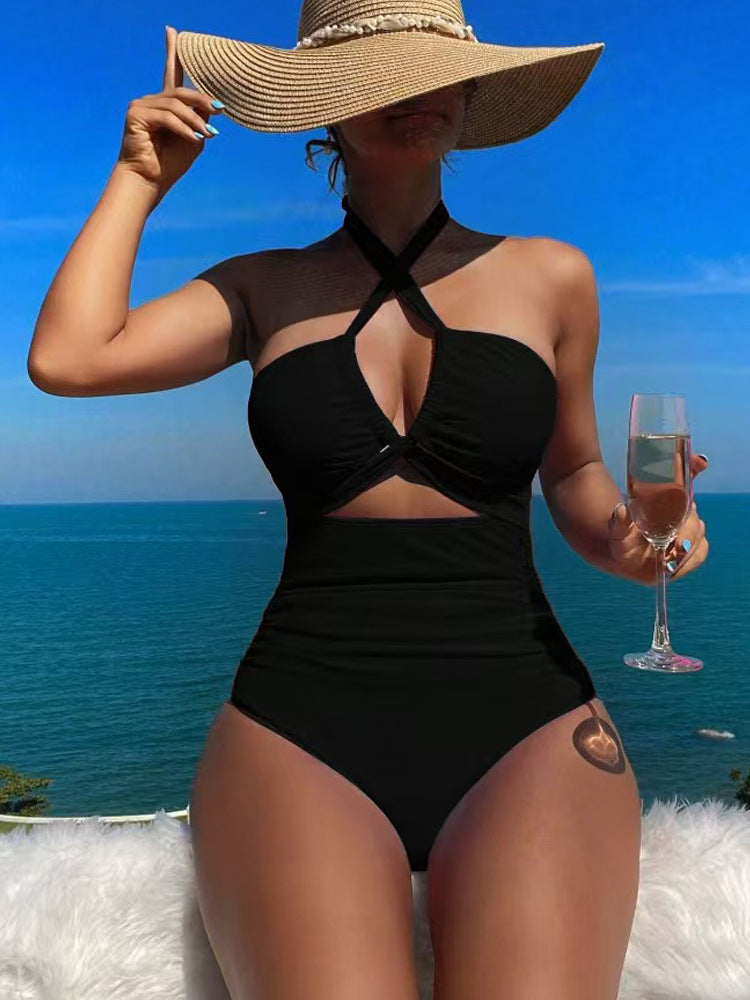 Woman in a black swimsuit holding a glass of pink champagne with a scenic ocean view.