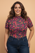 Woman wearing a colorful floral top and jeans against a beige background