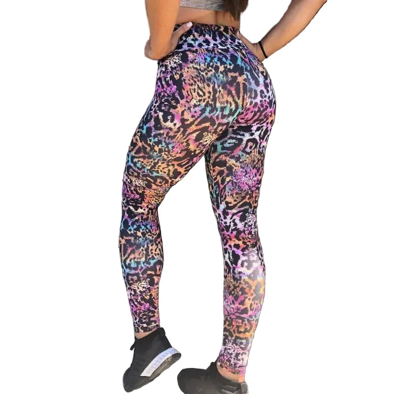 Person wearing colorful animal print leggings leaning against a gray wall.