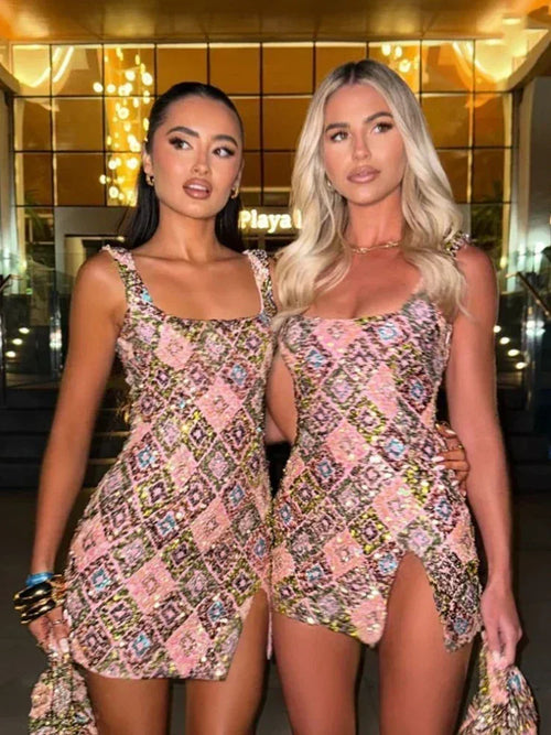 Two women wearing matching floral dresses standing in front of a building with reflective glass facade.