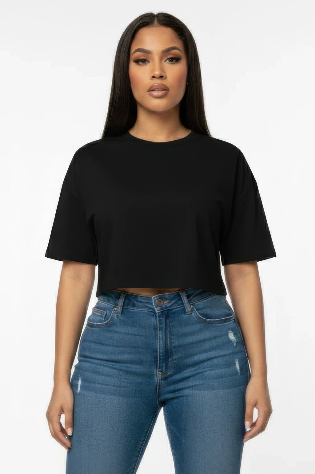 Woman wearing a black crop top and blue jeans on a white background