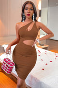 Woman in a brown dress posing in a room with a bed and decor.