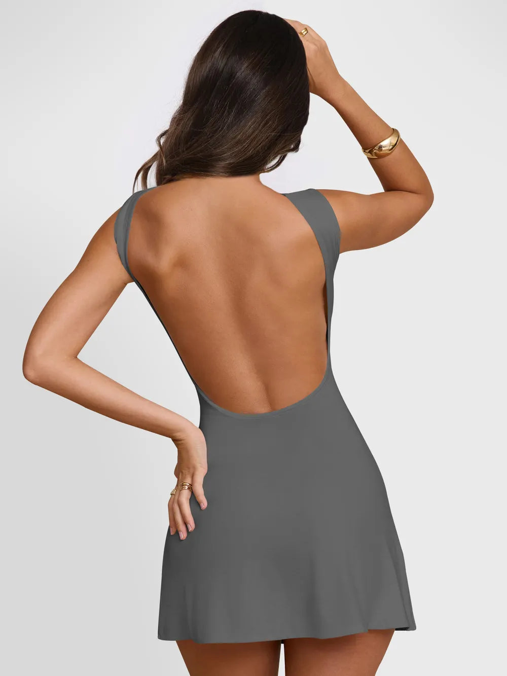 Woman wearing a gray dress with an open back on a white background