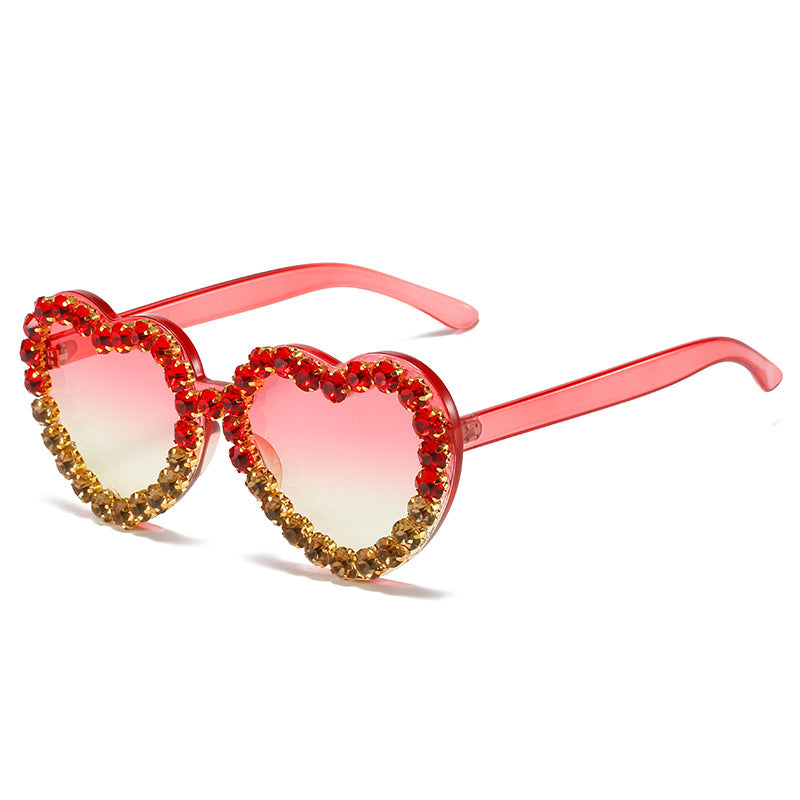 Heart-shaped sunglasses with red and gold embellishments on a white background