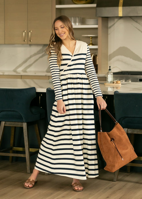 Woman in a long black and white striped dress standing in a kitchen.