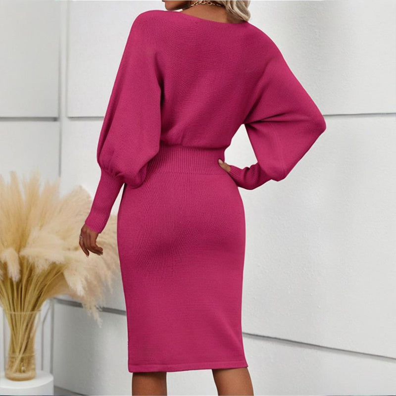 Person wearing a magenta dress with long sleeves in a minimal indoor setting.