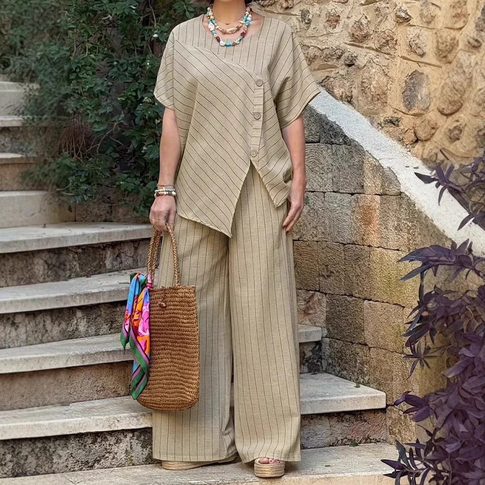 Woman in a beige outfit holding a woven bag on stone steps with a stone wall background