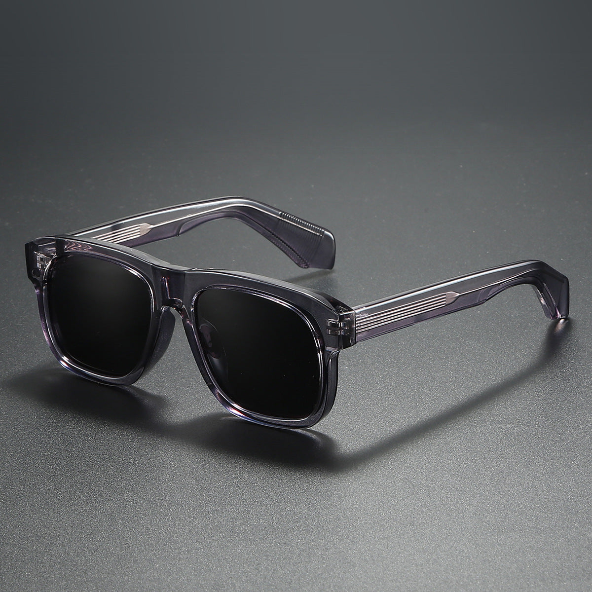 Sunglasses with clear frame and dark lenses on a gray background