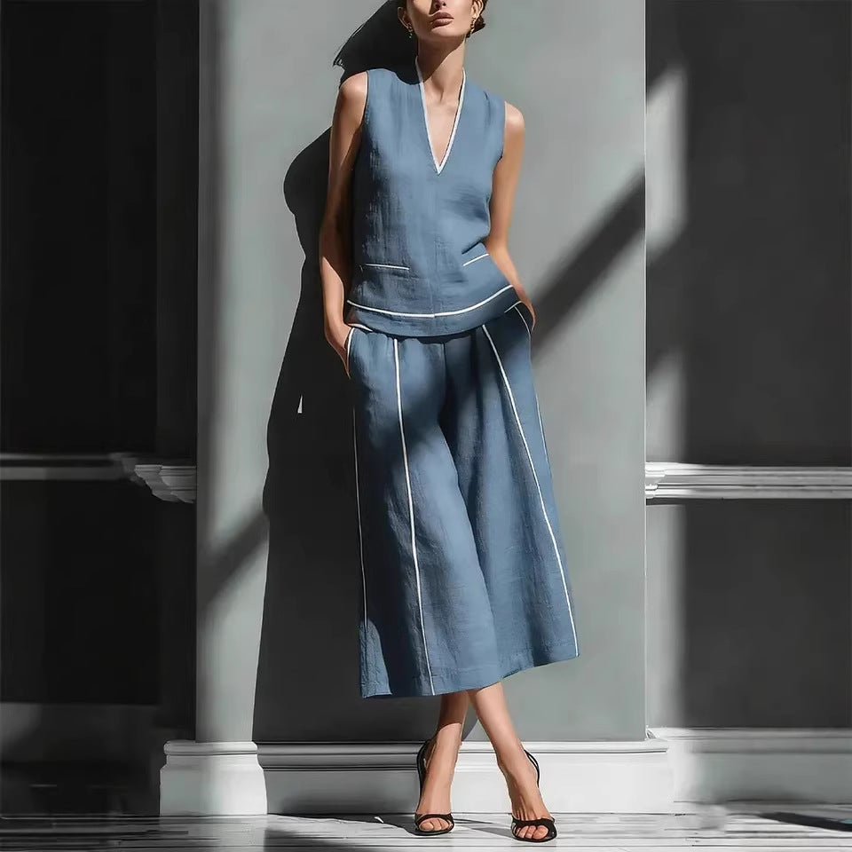 Woman wearing a blue sleeveless top and wide-leg pants in a minimalistic setting.
