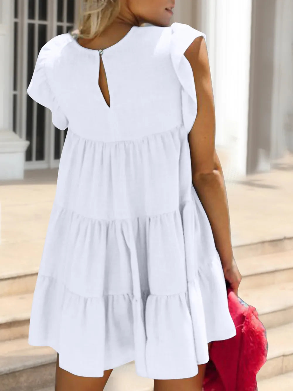 Woman wearing a white dress with a blurred background and showing the back of the dress
