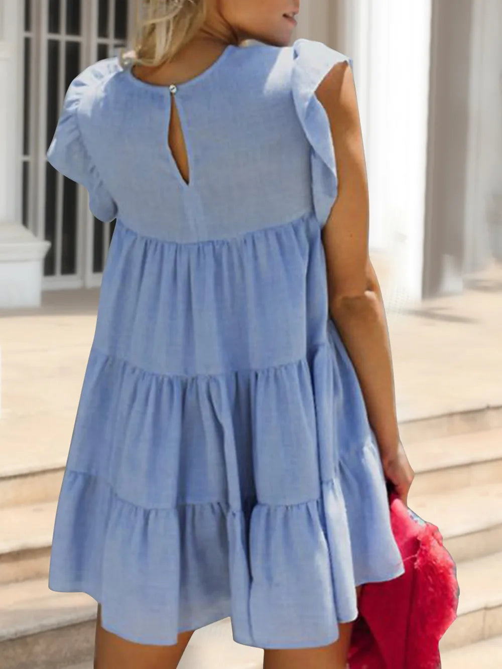 Woman wearing a light blue dress with a layered skirt in an outdoor setting.
