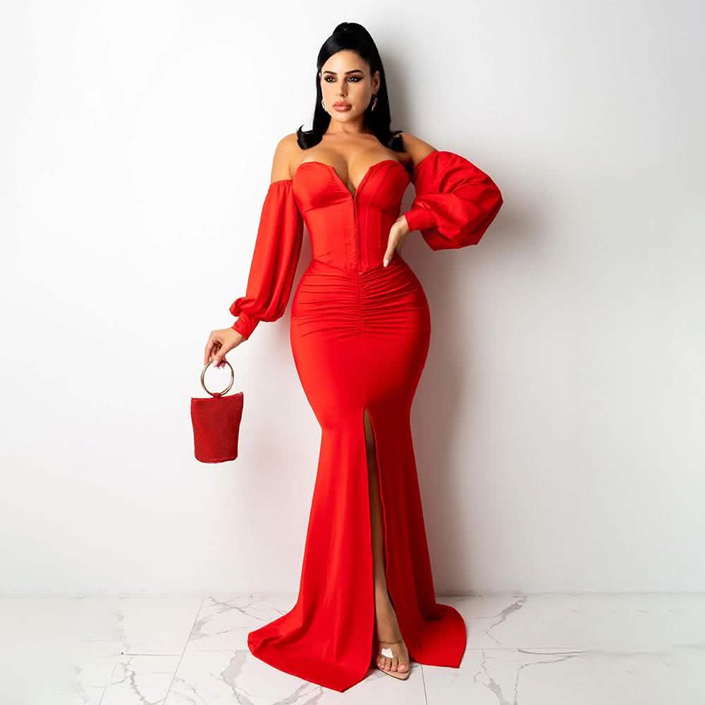 Woman in a red off-shoulder gown holding a matching handbag against a white background