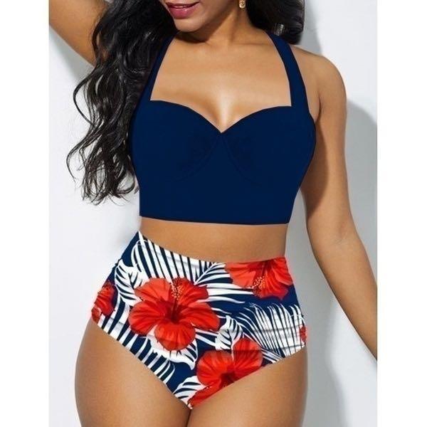 Woman wearing a navy blue bikini top and floral high-waisted shorts on a white background