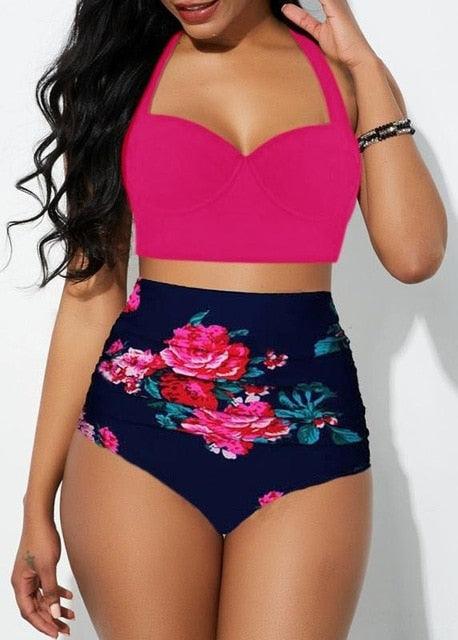 Woman wearing a pink bikini top and navy floral high-waisted bottoms on a white background