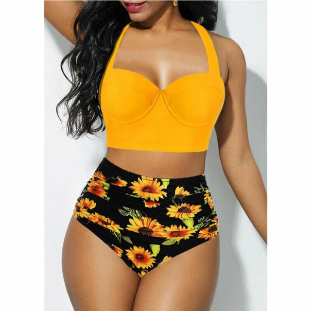 Woman wearing a yellow bikini top and black floral high-waisted bottoms on a white background